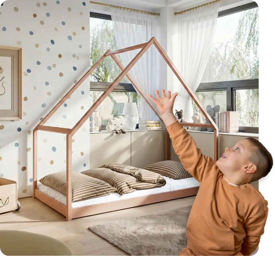 Chłopiec wskazujący na cynamonowe łóżko w kształcie domku za nim